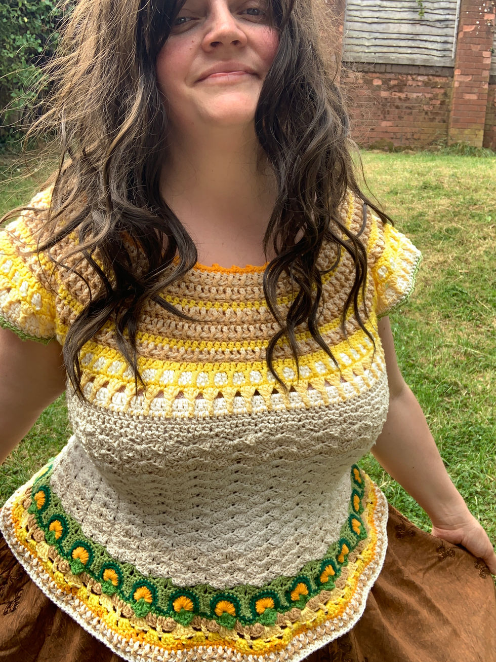 Woman wearing a yellow and tan crochet Frith Top smiling outside in the sun.