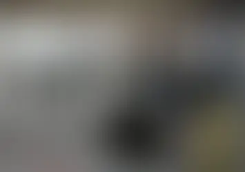 People gathered inside a large auto detailing shop with several cars being serviced.