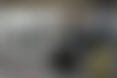 People gathered inside a large auto detailing shop with several cars being serviced.