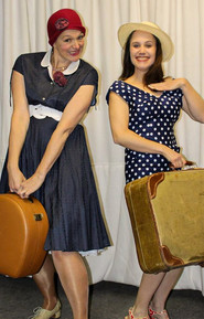 Zwei Frauen in Vintage-Kleidern mit Koffern