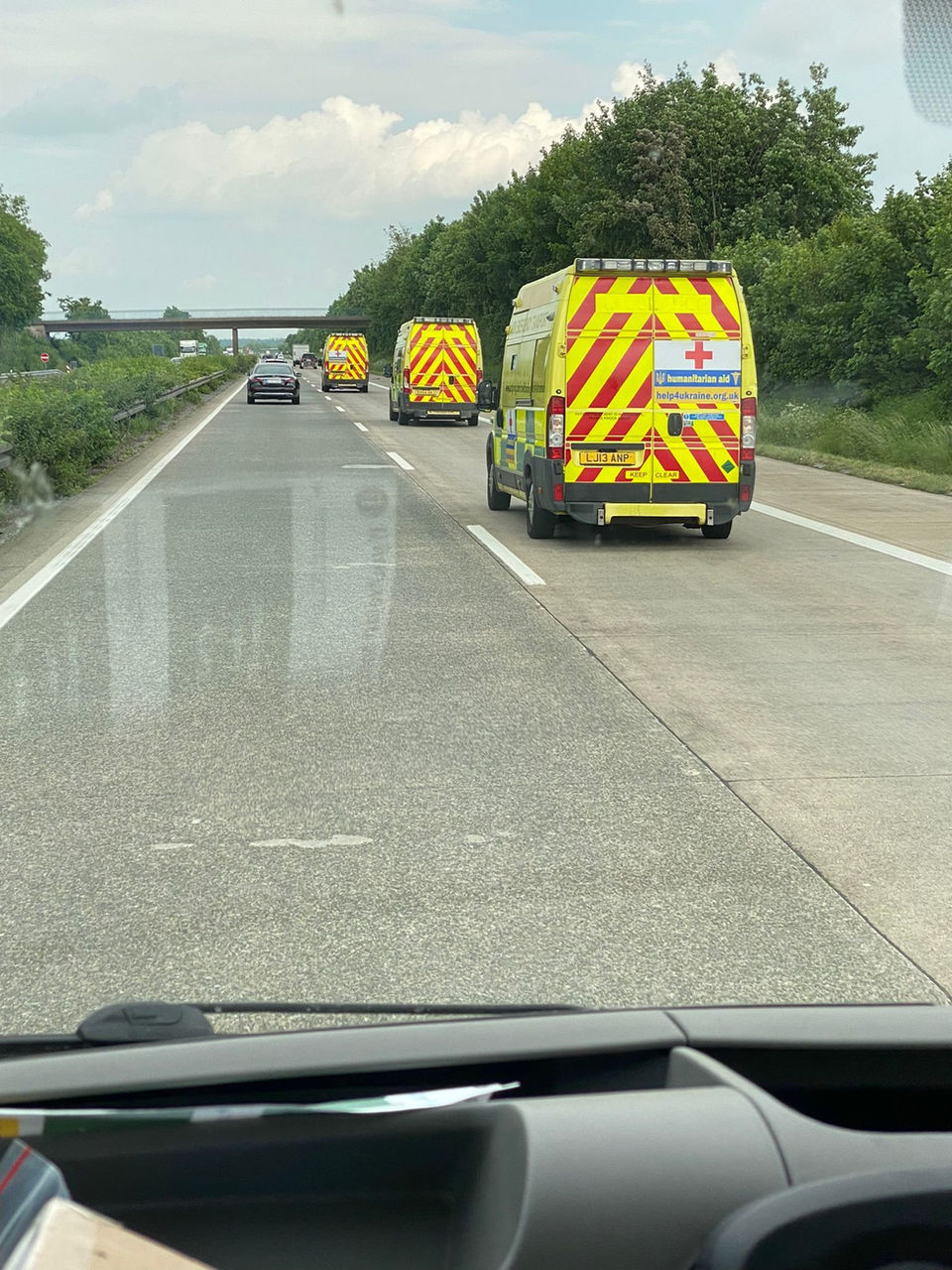 A couple of trucks driving down a road next to a forest