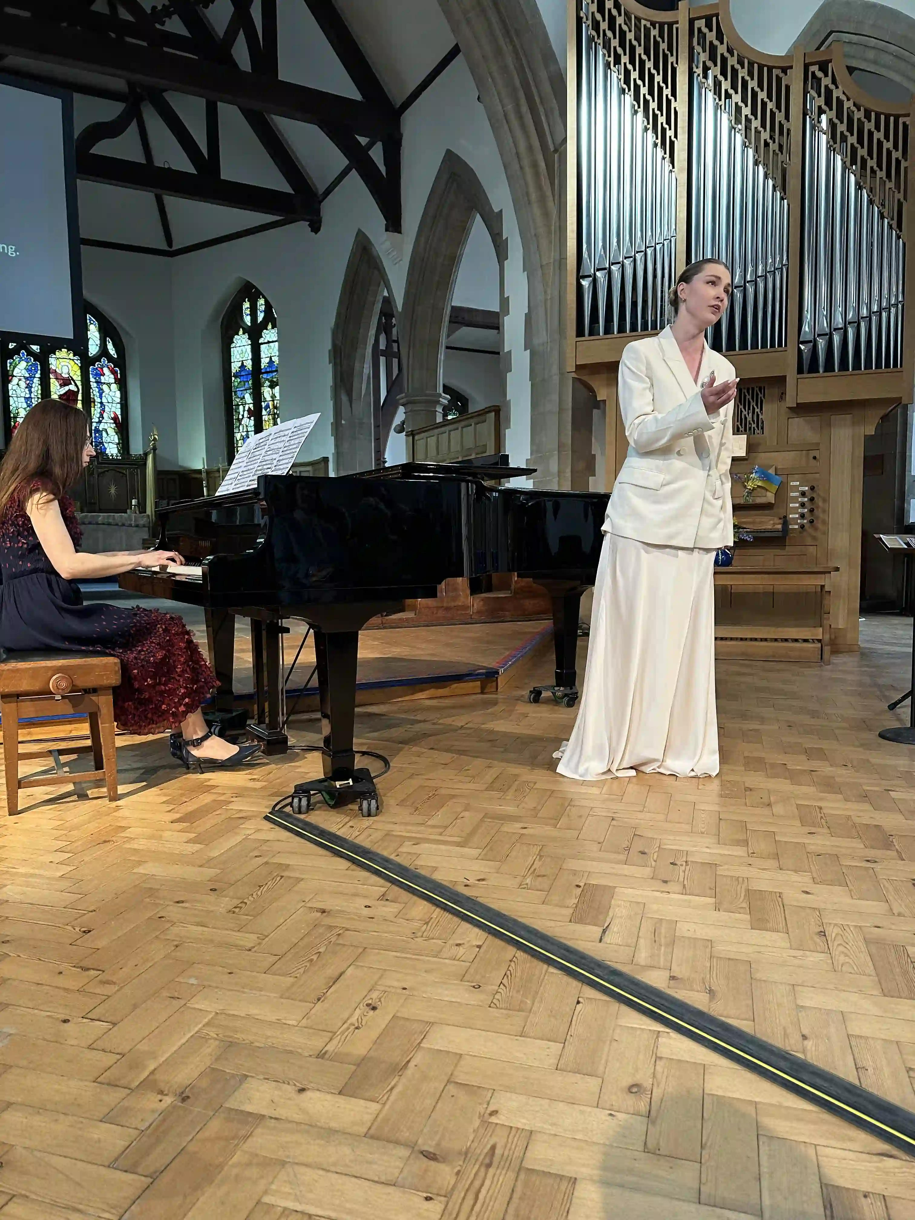 A woman in a white dress standing in front of a piano