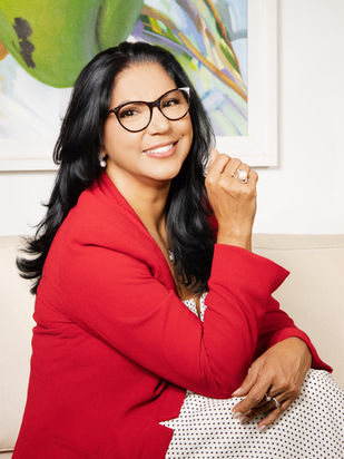 Escritora sorrindo utilizando uma roupa vermelha, olhando sorridente para câmera