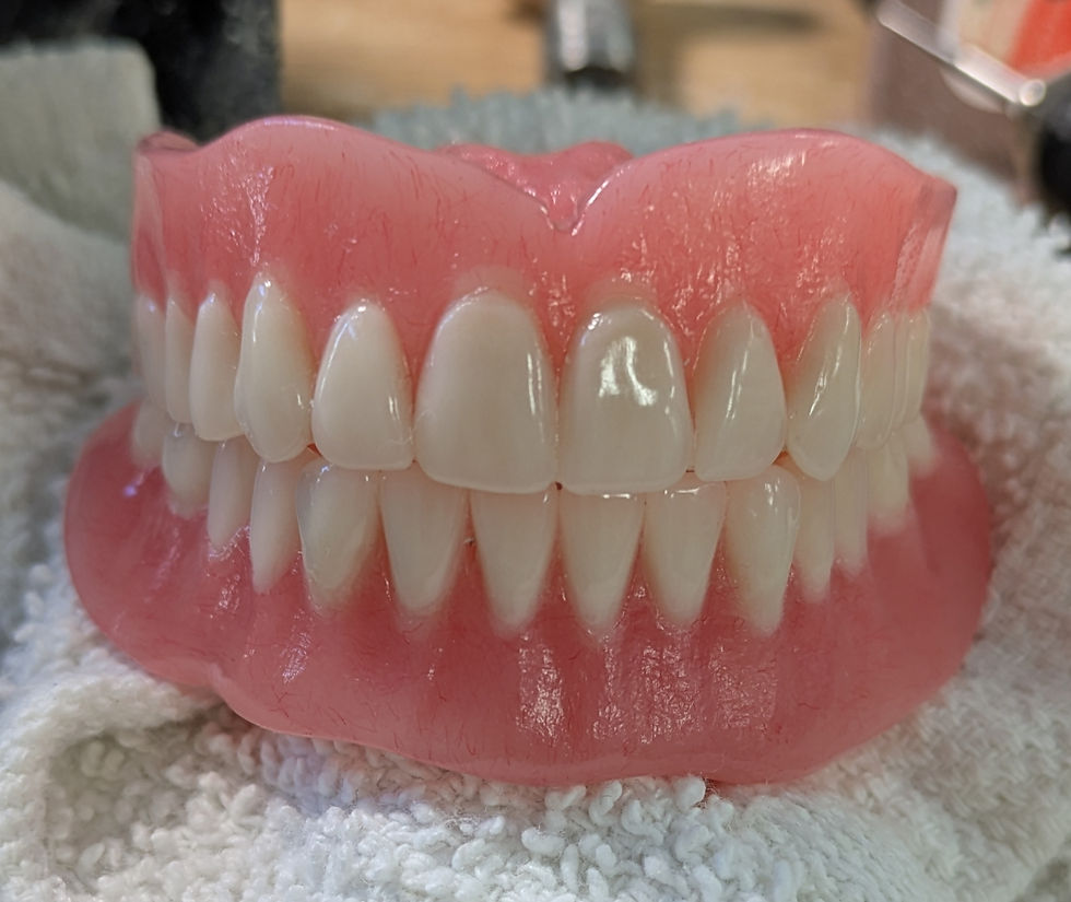Dentures with straight but natural looking teeth and pink gums, created by NALDIS Dental