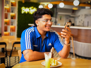A SmartQ employee sitting at a cafeteria table and looking at his phone