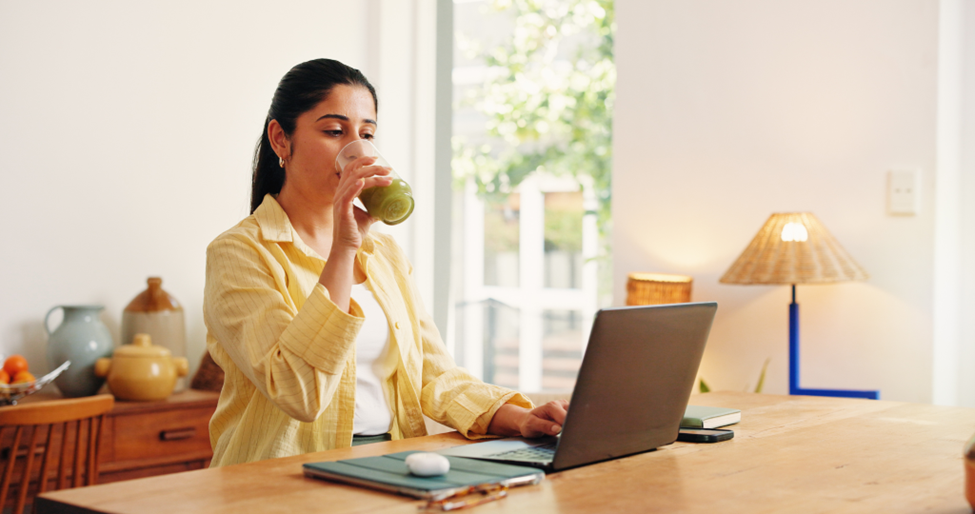 A woman drinking healthy juice while working