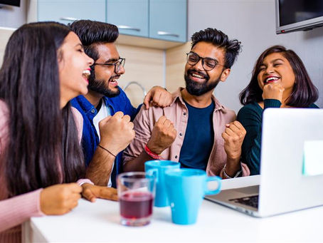 Group of office employees chatting and relaxing in the workplace pantry during a coffee break.