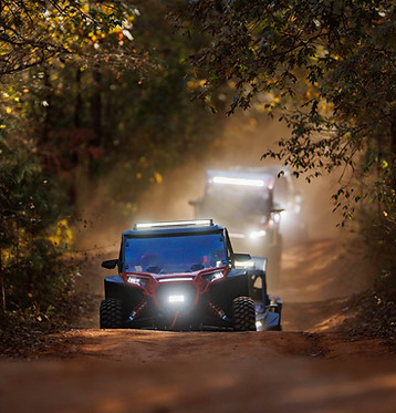 A polaris RZR UTV, riding on a dirt trail at dusk.