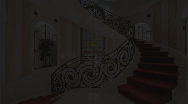 Curved staircase with ornate wrought iron railings.