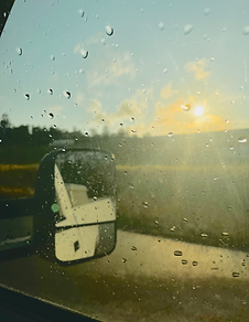 Scenic sunrise with a truck's rear view mirror in the foreground.