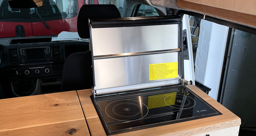 Camper Van mit individuellem Innenausbau auf Basis eines VW T6 Transporters mit GFK-Hochdach. Möbel aus hellem Holz und Fichten Paneele als Highlight, Arbeitsplatte aus Eiche lackiert und Schlafsitzbank. Energieautark campen dank durchdachter Ausstattung. Möglichkeit für den Transport eines Motorrads. 