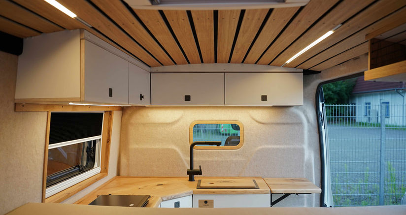 gemütlicher Camperausbau auf Basis eines Ford Transit. Kontraststarke Farbgestaltung weiße Möbel treffen dunkle Eiche 