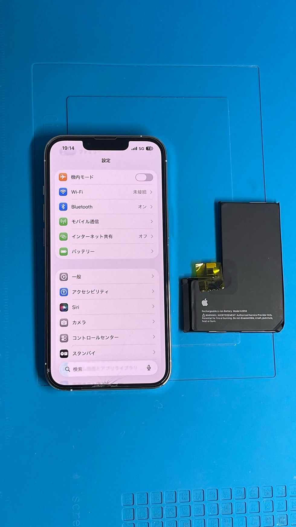 バッテリー交換後に起動と基本動作を確認したiPhone 13 Proと取り外した旧バッテリー