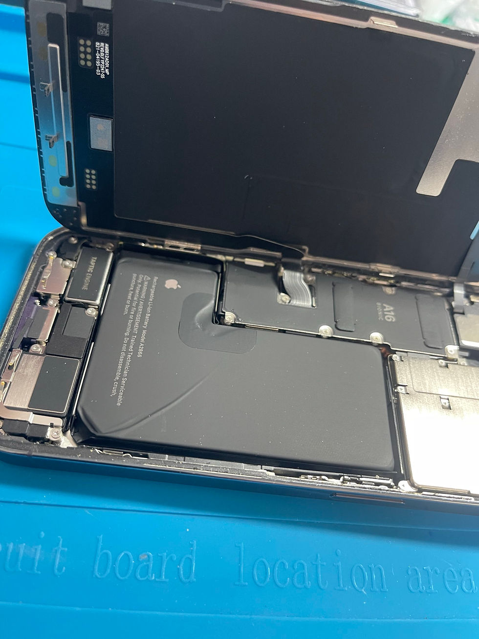 iPhone14 Proを分解し、内部のバッテリーと基板周辺を確認している修理作業中の写真