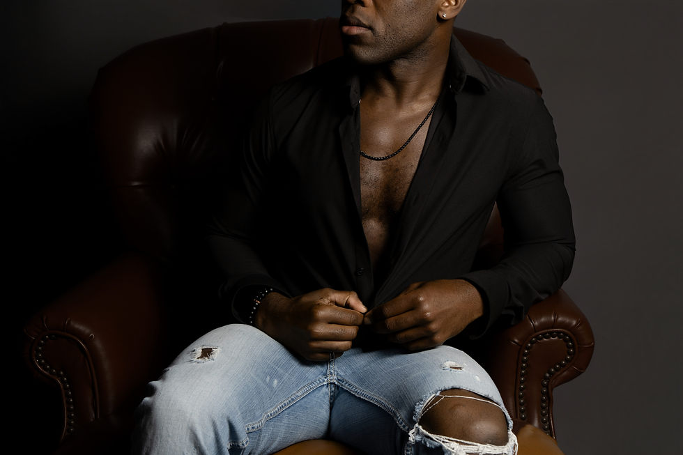 Black Man unbuttoning his shirt while sitting on a chair during a male boudoir session at a Dayton Ohio studio