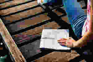 woman sitting on brown wooden dock and holding mop