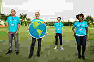 group of four people wearing blue standing on green grass field