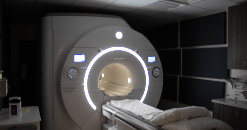 An MRI machine glowing in a dark patient room.