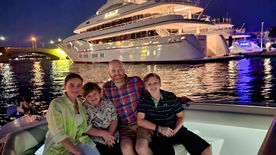 As the sun sets, the night lights glow with a family on board the Bonnie Lee with a Mega Yacht in the background in full lights