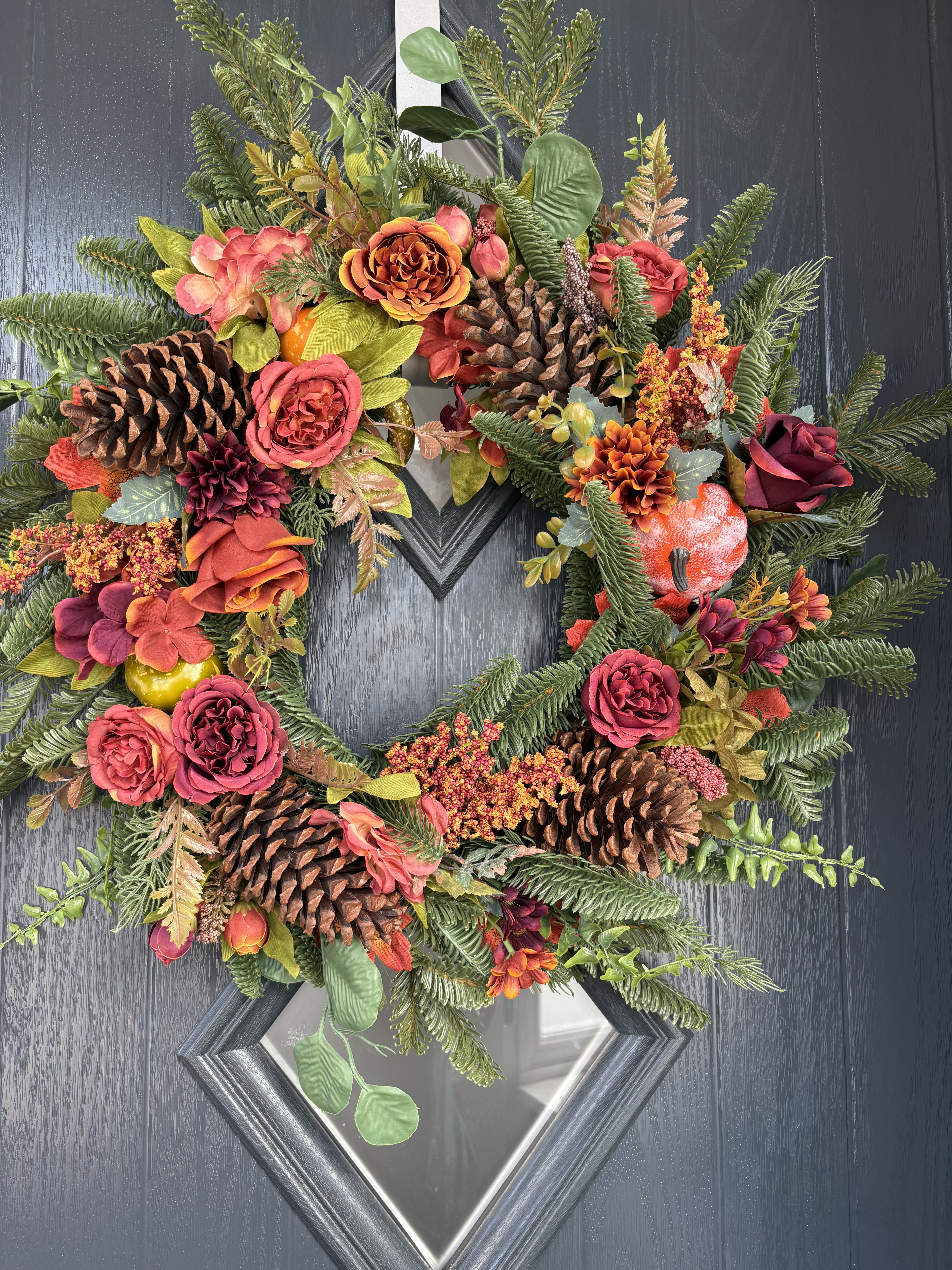 Vibrant summer door wreath with large artificial peonies and lush green leaves.