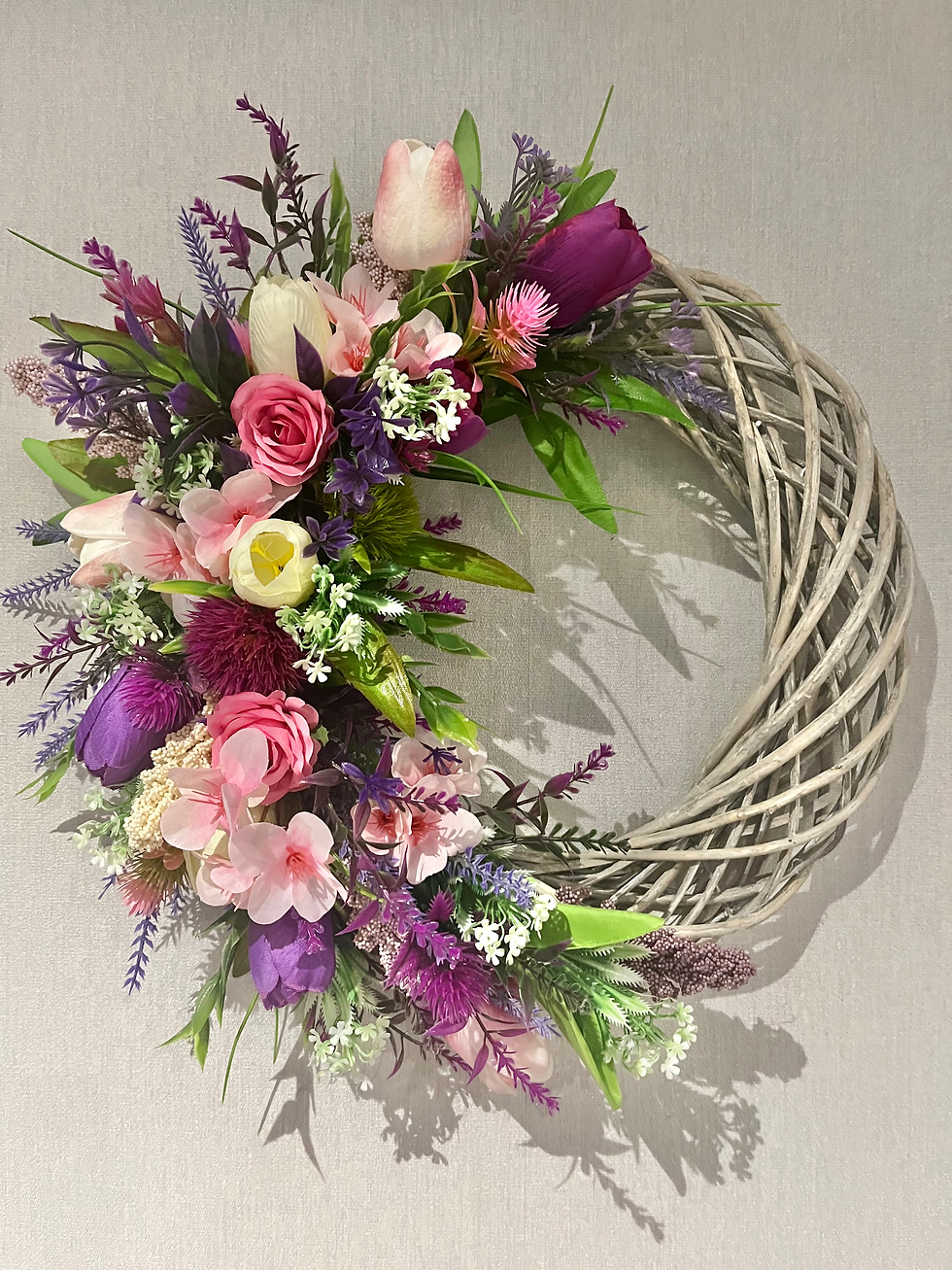 Grey wicker wreath with pink and purple flowers