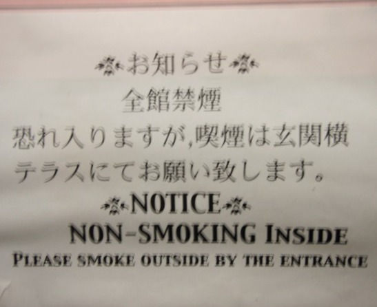A funny no smoking sign from Japan advising people to smoke by the doorway