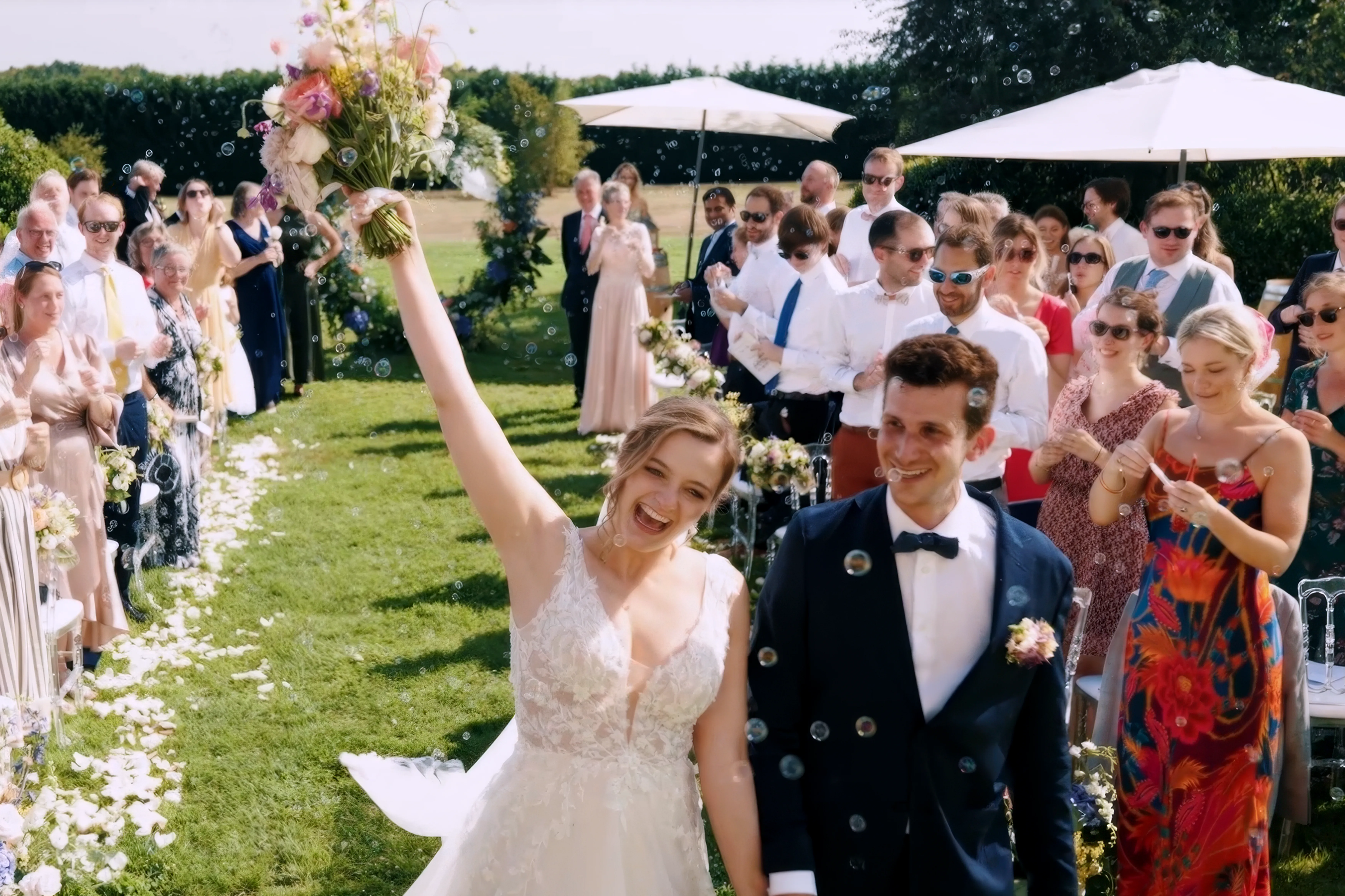 Sortie de cérémonie laïque, la mariée levant le bras en l'air, capturée par HDAS Records, photographe à Bordeaux