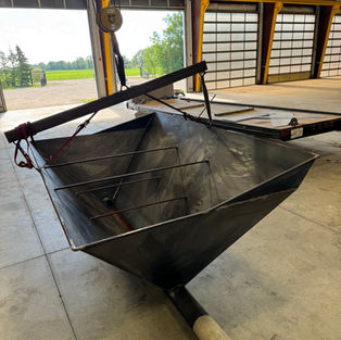 Industrial steel hopper fabrication project showing custom welded hopper during overhead lift testing in a fabrication shop.