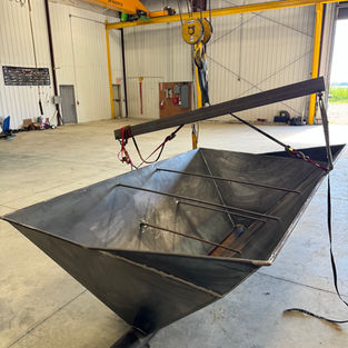 Custom fabricated steel material handling hopper featuring tapered sidewalls, internal reinforcement bars, and a center discharge outlet for efficient bulk material flow.