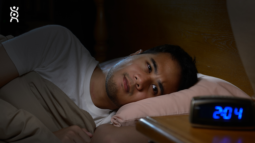 Hombre despierto en la cama, mirando pensativo; reloj digital azul marca 2:04 en una habitación oscura y tranquila.