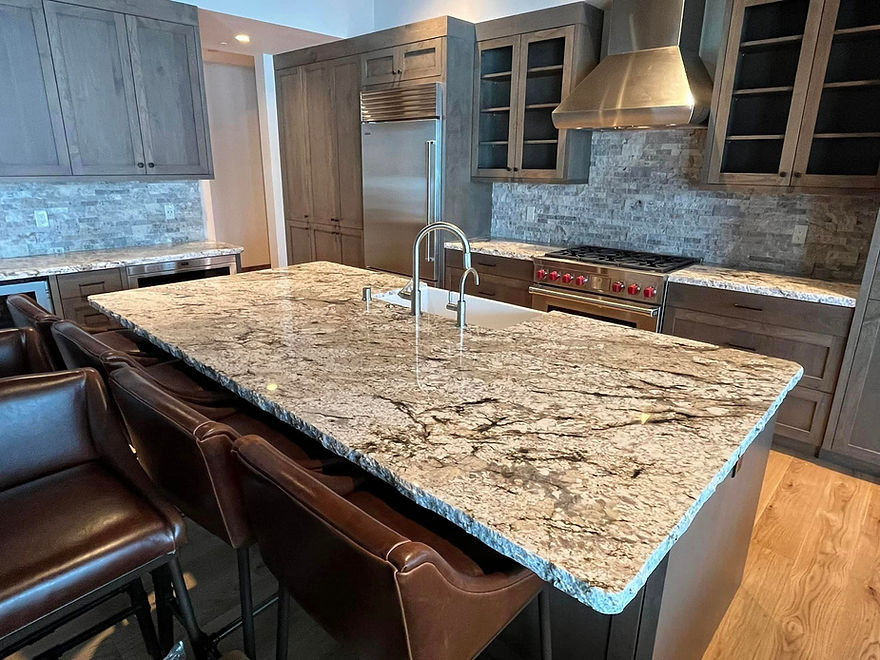 modern kitchen featuring a large granite countertop island with a built-in sink and a sleek faucet. The kitchen is equipped with stainless steel appliances