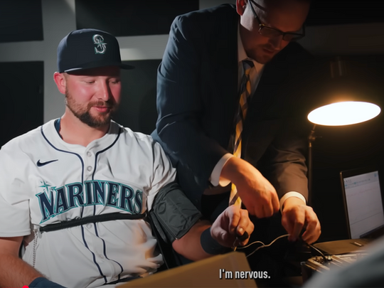 Mariners' Cal Raleigh getting hooked up to a polygraph by Detective Chris Brooks