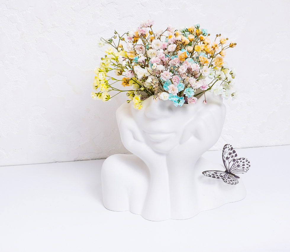 White vase shaped like a face holding colorful flowers, next to a black-and-white butterfly figurine on a white background.