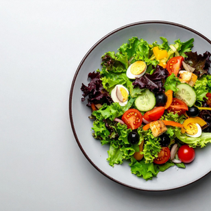 Colorful salad with lettuce, tomatoes, cucumbers, olives, eggs, and croutons on a gray plate, set against a plain light gray background.