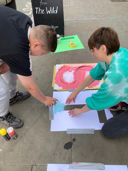 Two people stenciling The Wild Weed Kitchen logo