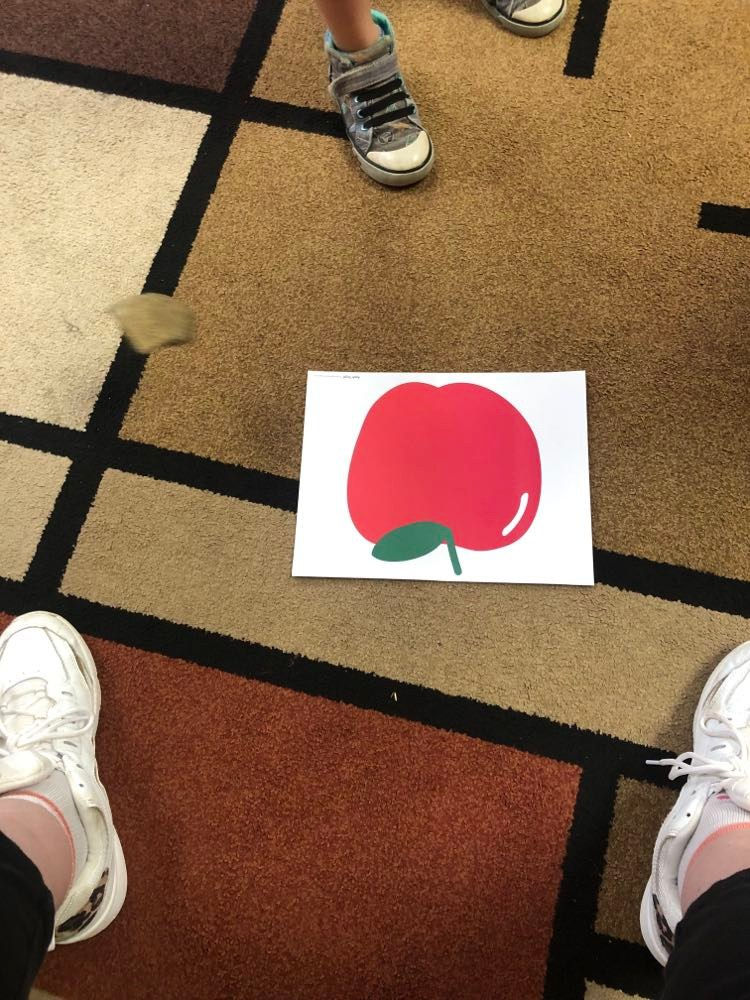 preschoolers dropping rock onto apple card on floor