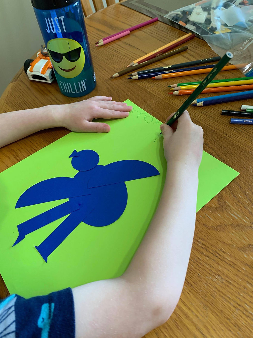 child making a bird collage using construction paper and colored pencils