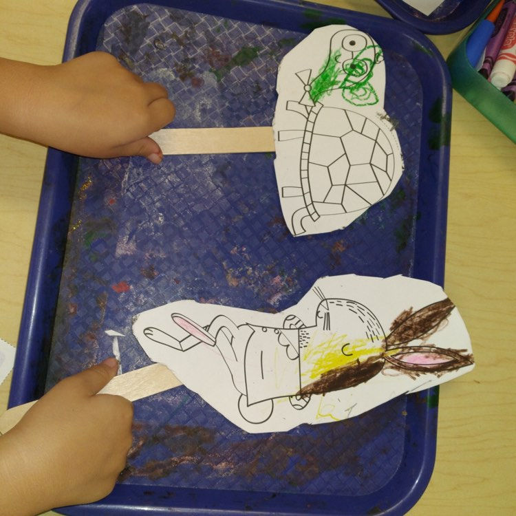 preschooler picking up hare and tortoise puppets