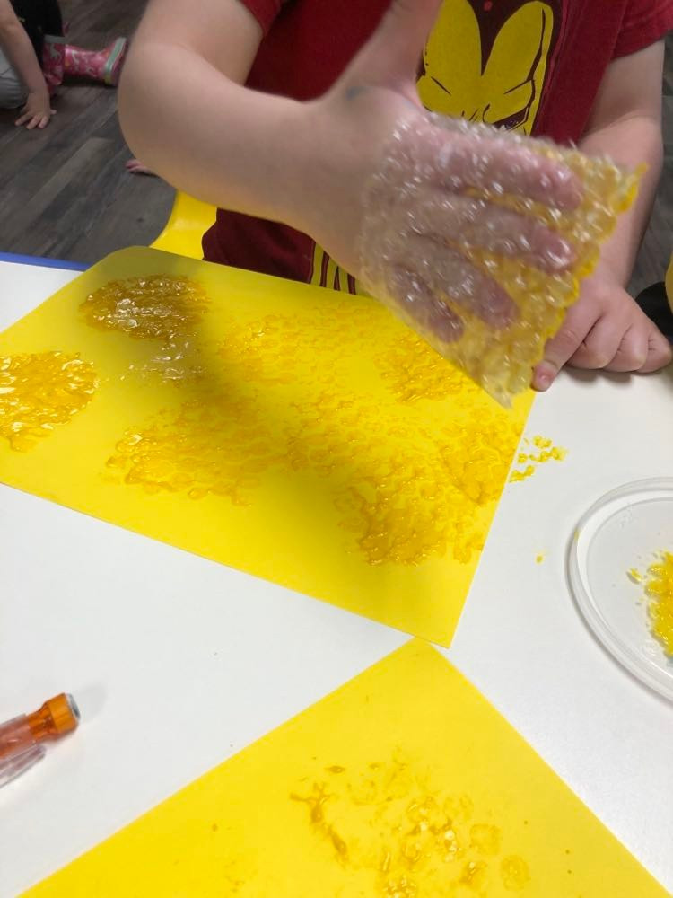 preschooler using bubble wrap to stamp on yellow cardstock