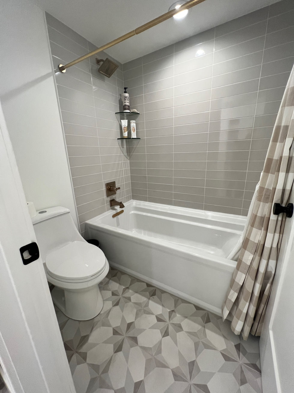 Small, modern bathroom with bathtub and checkered floor.