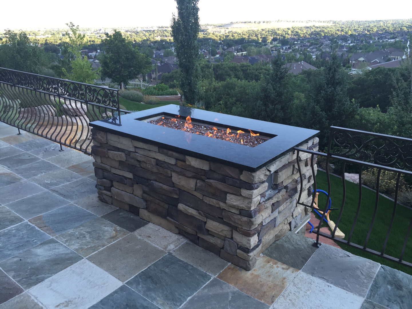 Stone fire pit on a patio with scenic view.