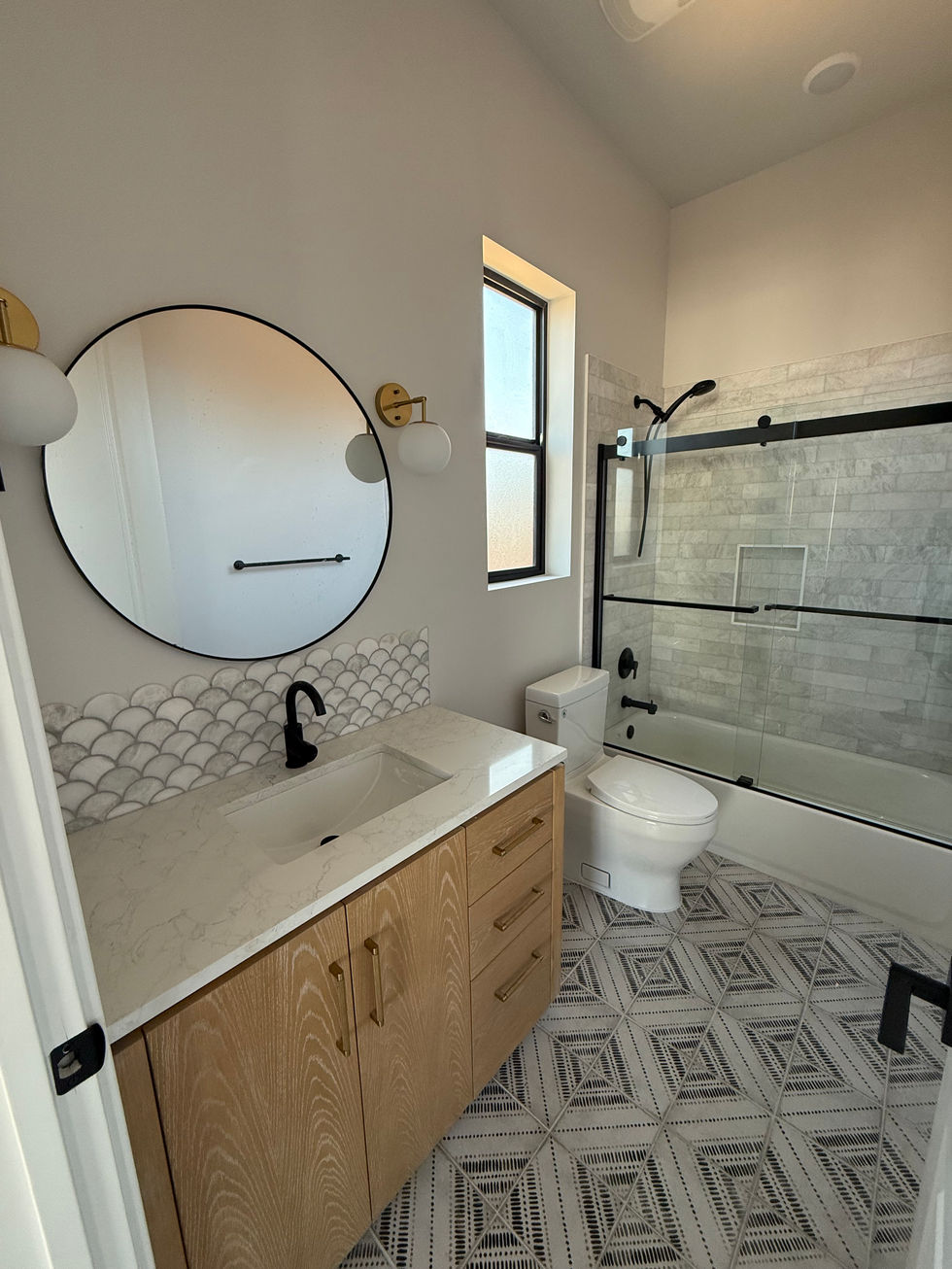 Modern bathroom with round mirror and glass shower.
