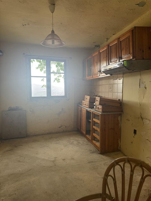 Kitchen in an authentic house for sale near Vasiliki with wooden cabinets and a window