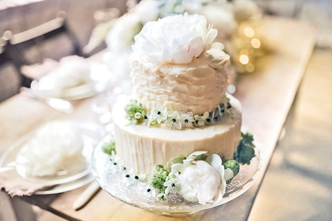 Three-tiered wedding cake with white flowers and decor. Simply Radiant Sweets LLC.