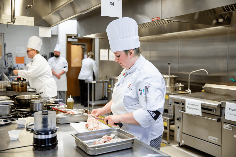 A student cooks over a stove.