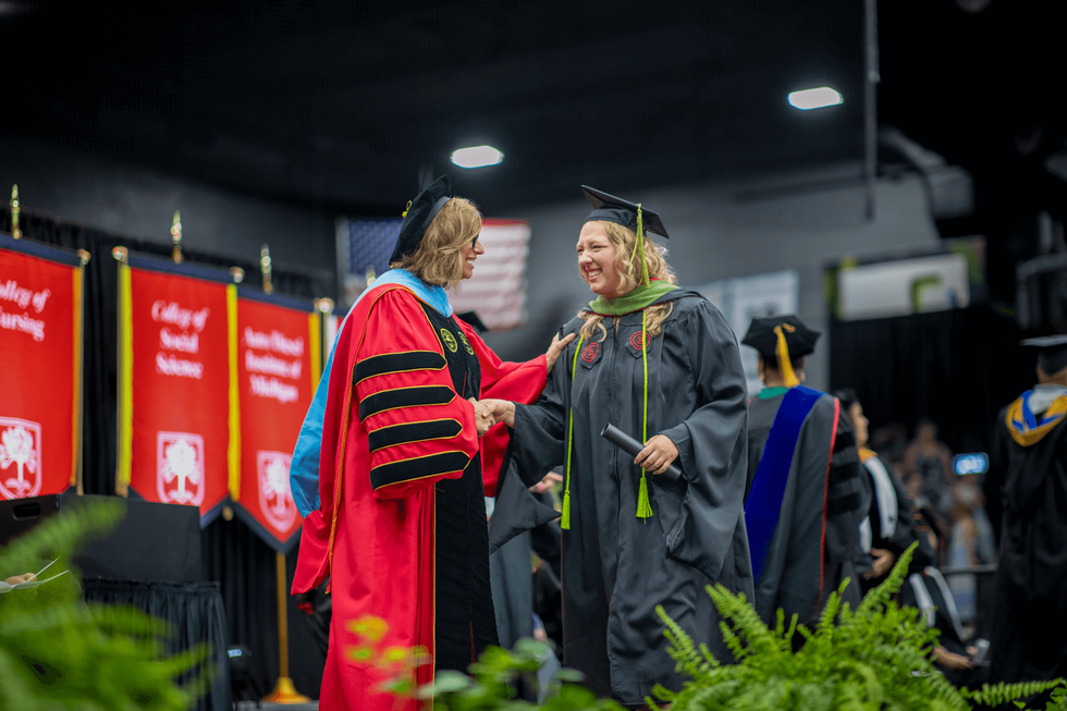 A graduate accepts her degree from the college president.