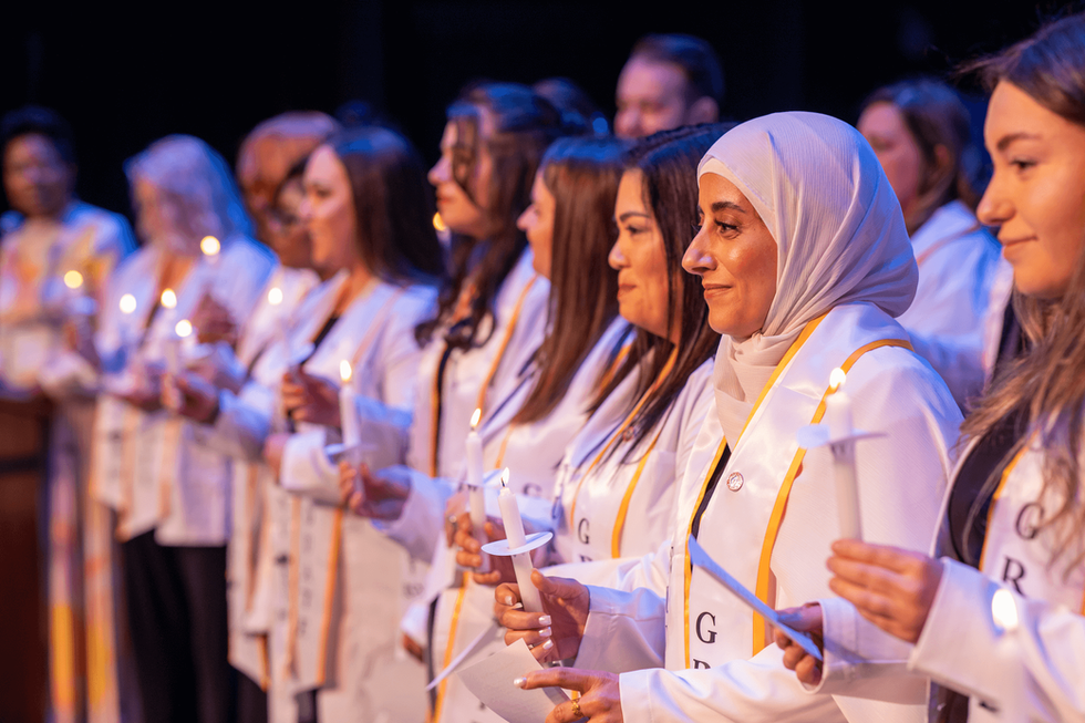A line of nursing students stand with candles.