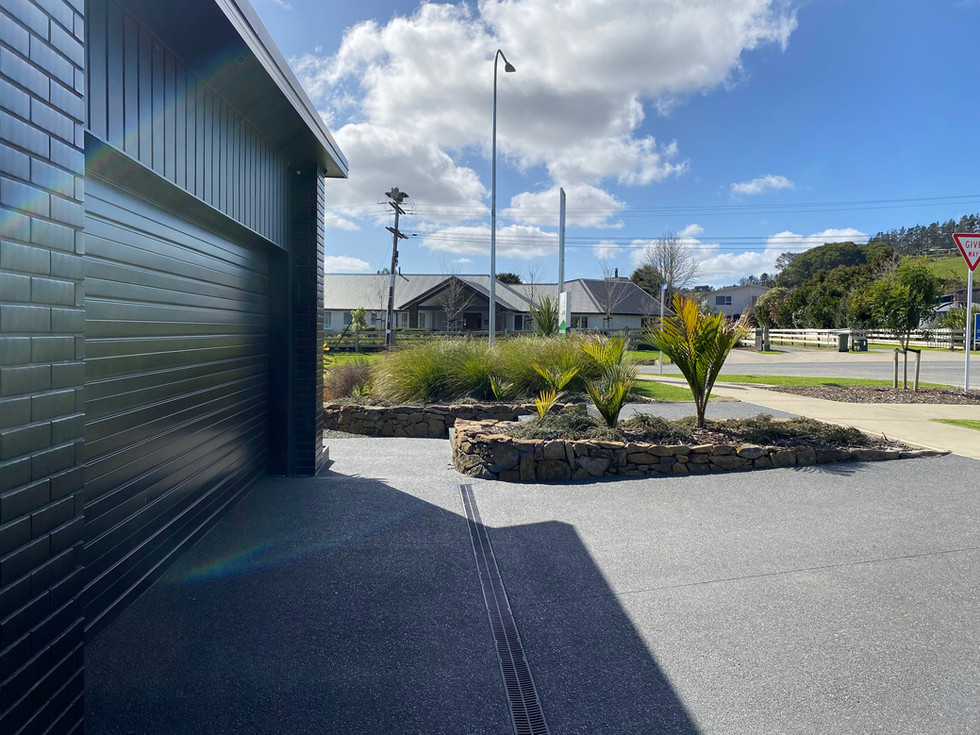Exposed aggregate, with 5kg black oxide. Driveway with channel drain.