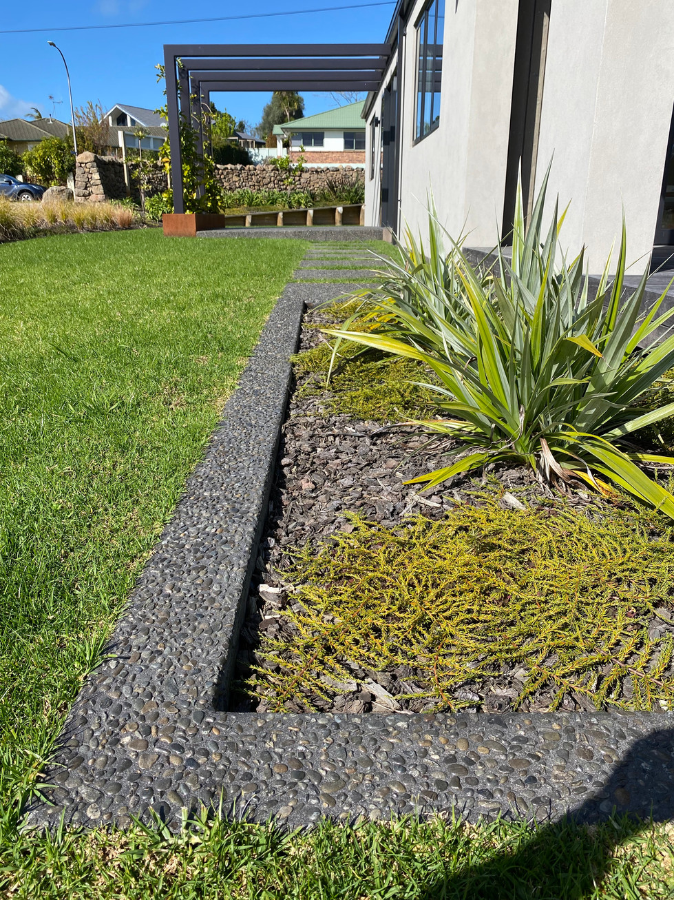 Exposed Awatoto Pebble, with 10kg black oxide. Concrete sealed. Mowing strip.