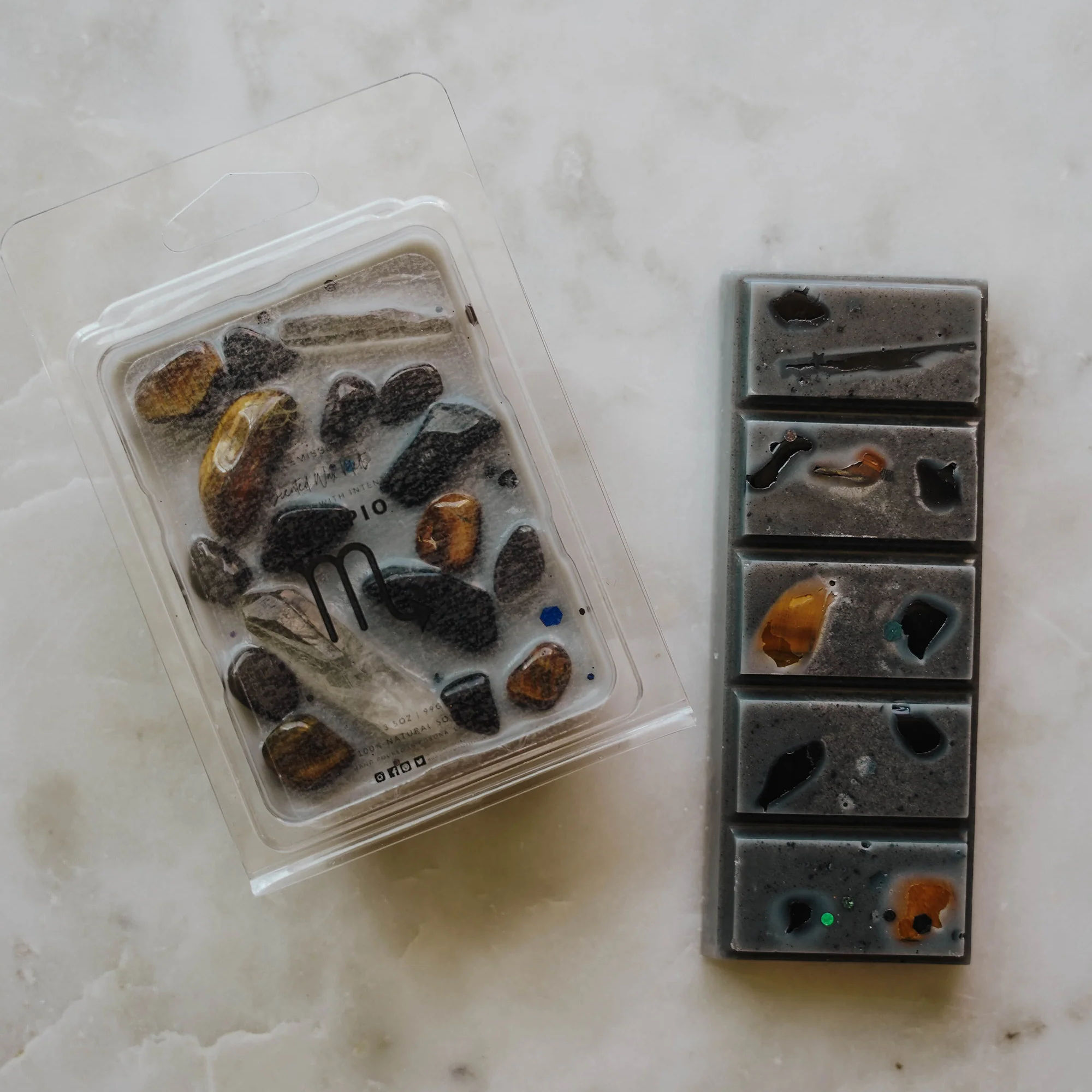 Scorpio zodiac wax melt and snap bar in black tones with crystals, displayed on cream marble surface